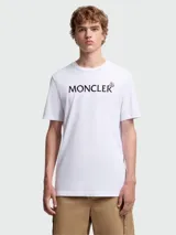 Camiseta blanca de manga corta con cuello redondo y el logo de Moncler estampado en negro en el pecho.