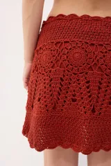 Minifalda tejida a crochet color ladrillo, con cintura alta y cordón trenzado con borlas.