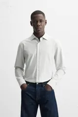 Camisa celeste a rayas verticales blancas, de corte recto, con cuello italiano abierto, mangas largas con puños abotonados y cierre frontal con botones.