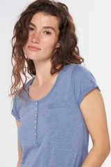 Remera color beige con escote redondo, manga corta, bolsillo en el pecho y cierre parcial con botones.