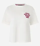 Remera blanca de algodón con corte boxy, cuello redondo y mangas cortas con dobladillo. Presenta un bordado en el pecho con la frase "PEACE NEW YORK MONEY WINE" en color borgoña.