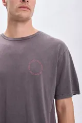 Remera de manga corta gris oscuro con estampa circular en la espalda con un sol en el centro y la frase "Catch the sun, chose the surf".