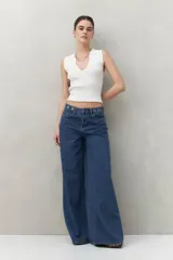 Pantalón de jean azul oscuro, corte ultra wide, tiro medio y detalles metálicos en la cintura.
