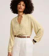 Camisa de viscosa color amarillo pálido con estampado de follaje, cuello mao, cierre frontal con botones y mangas largas con puños ajustados.