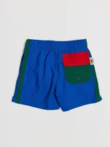 Short de baño azul con cintura elástica, rayas verdes en los laterales y bolsillo trasero con solapa roja y verde.