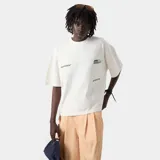 Camiseta color arena de corte cuadrado con cuello polo y estampado en la espalda con el logo de la marca Eme Studios y la frase "Building a community through gratitude".