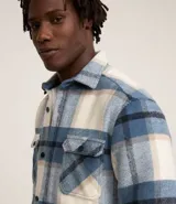 Campera trucker masculina de terciopelo a cuadros en tonos azul, blanco y beige. Tiene cuello inglés, cierre abotonado, bolsillos delanteros y laterales.