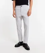 Pantalón de hombre color gris claro, corte slim, confeccionado en sarga leve. Cuenta con cierre de botón y cremallera, y bolsillos.