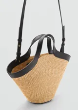 Bolso tipo tote de paja color beige con detalles en cuero sintético negro. Tiene doble asa de mano y correa larga al hombro.