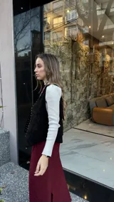 Chaleco negro de cuero descarne con terminación en picos y tachas metálicas.