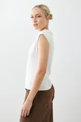 Remera blanca de corte ajustado, con cuello alto y sin mangas.