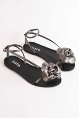 Sandalias bajas de cuero color suela, con tiras finas y aplique de flor roja en el empeine.