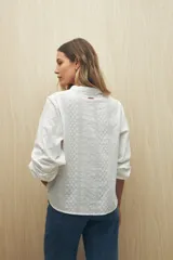 Camisa blanca bordada de algodón con diseño floral y calados, escote en V con cuello mao y mangas largas.
