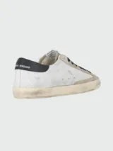 Championes urbanos Golden Goose modelo Super Star, color blanco con detalles en gris y estrella azul en el lateral.