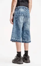Bermuda de denim larga con calce oversize, desgaste y ruedo desflecado.