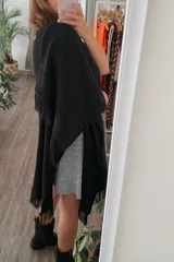 Ruana tejida color negro con diseño calado y flecos en los bordes.