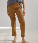 Pantalón largo de lino color marrón, con corte cigarette, tiro alto, bolsillos laterales y traseros con pespuntes a la vista, y etiqueta de cuero con logo en la cintura.