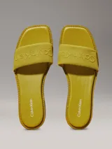 Ojotas amarillas de lona con logo de Calvin Klein grabado en la tira.