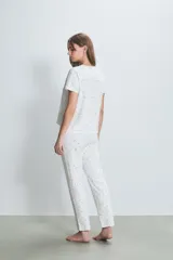 Conjunto de pijama blanco con estampado de lunares negros, compuesto por una remera de manga corta y un pantalón largo.