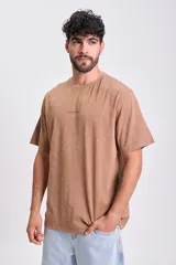 Remera marrón de manga corta con corte oversize y estampa en la espalda con la frase "Each corner of the world has a story to tell".