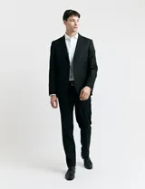 Traje de vestir negro, compuesto por saco de corte clásico con solapas de muesca, cierre de dos botones y pantalón de corte recto.