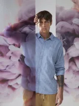 Camisa celeste de lino con cuello clásico, manga larga con puños abotonados y bolsillo de parche en el pecho.