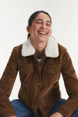 Campera de ante sintético color marrón con forro de sherpa y cuello de piel sintética.