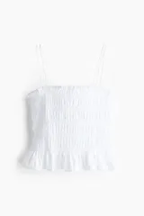Top blanco de algodón con escote recto, breteles finos y volado en el bajo.