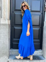 Vestido largo azul eléctrico con escote en V, mangas cortas con detalle de lazo y falda con volantes.