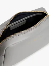 Cartera bandolera rectangular de cuero sintético color gris claro, con cierre superior de cremallera y logo metálico de Tommy Hilfiger en el frente.