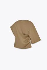 Camiseta color marrón con cuello redondo, manga sisa caída en un lado y manga corta en el otro. Tiene detalle de frunces laterales.