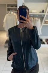 Campera de cuero ovino italiano color negro, con cuello a la base, cierre frontal con cremallera plateada, bolsillos laterales y corte clásico.