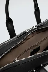 Maletín negro con acabado texturizado, compartimento principal con cierre de cremallera, bolsillo interior con cremallera, bolsillo frontal con cremallera, bolsillo trasero para dispositivos electrónicos de hasta 13 pulgadas y bolsillo trasero con cremallera. Tiene dos asas de mano y un asa de hombro ajustable y extraíble.