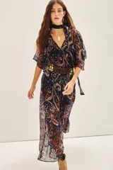 Vestido largo con estampado paisley en tonos azul, negro, rojo y dorado. Tiene escote en V, mangas cortas amplias, elástico en la cintura con lazo y está confeccionado en viscosa con jacquard de lurex.