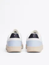 Zapatillas Tommy Hilfiger de cuero sintético color celeste con detalles en blanco y suela color crema. Presentan el logo de la marca bordado en el lateral y detalles distintivos en el talón.