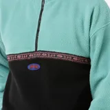 Canguro de polar multicolor con cierre parcial, cuello alto y puños elásticos. Presenta un diseño de bloques de color en tonos celeste y negro, con una banda estampada en el pecho y logo bordado.