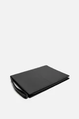 Bolso tipo sobre negro de cuero, con costura central y asa de mano. Cierre con cremallera y compartimentos interiores.