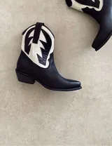 Botas cortas negras de cuero con bordados blancos estilo cowboy.