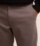 Pantalón de vestir marrón, de corte skinny, con bolsillos laterales y traseros. Se ajusta a la cintura con cinturón de cuero marrón.