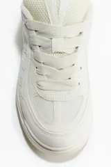 Zapatillas deportivas de estilo skate color crema, confeccionadas en malla y tejido revestido. Presentan cuello y lengüeta acolchados, cordones y trabilla trasera. Forro de tejido rizado y plantillas de piqué. Suela con diseño y grosor de 4,1 cm.