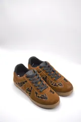 Zapatillas urbanas de cuero color crema con detalles en gris y suela de goma marrón.