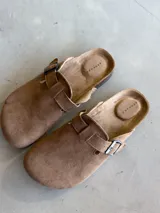 Zuecos color camel con hebilla metálica ajustable y suela de corcho.