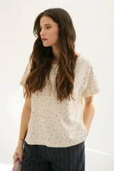 Blusa color crema con estampado de lunares negros, cuello redondo y mangas cortas.