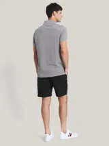 Chomba gris de corte regular, con cuello tipo chomba, cartera de dos botones, mangas cortas y logo de Tommy Hilfiger bordado en el pecho.