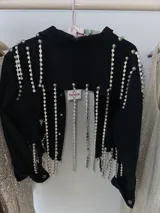 Campera cropped de jean negra con tiras de strass plateado y botones plateados al frente.