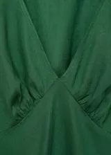 Vestido midi verde esmeralda de lino con escote en V, mangas cortas abullonadas y corte ajustado en la cintura.
