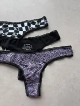Pack de tres colaless de algodón y lycra con detalles de encaje. Incluye una colaless a cuadros blancos y negros con diseño de yin yang, una negra con la frase "Be your beautiful self" y una con estampado de cebra en tonos lila y negro.