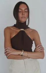 Top blanco sin mangas con cuello halter y detalle de anillo metálico en el centro.