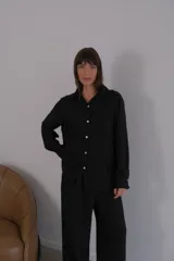 Camisa negra de crepé con cuello clásico y mangas largas.