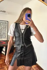 Minifalda negra de cuero con tajo lateral y detalle de cordones en el frente.